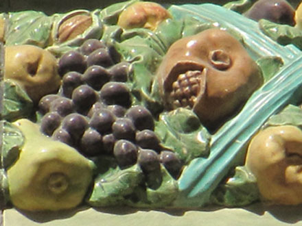 Raisin, et autres fruits locaux et exotiques enserrés par un ruban, terre cuite émaillée de Janin & Guérineau, à Paris (75)